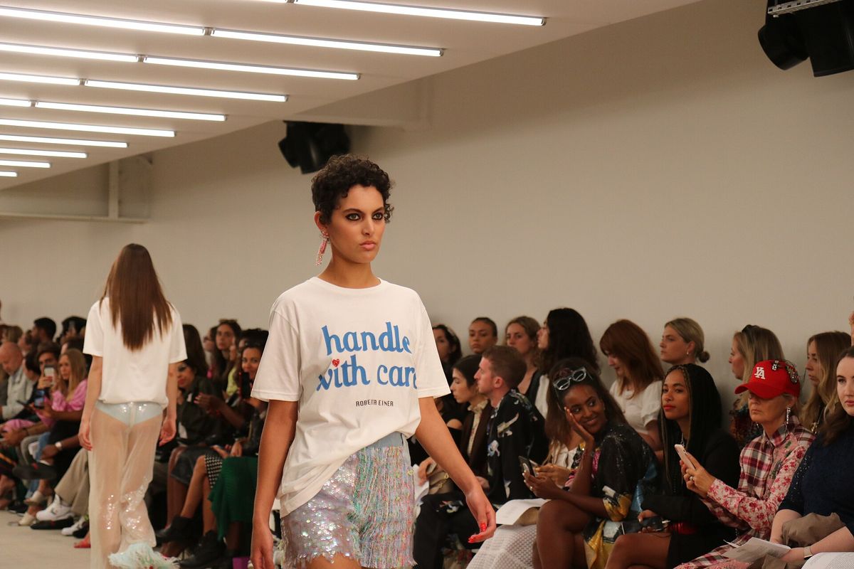Model on the runway at Roberta Einer's London Fashion Week show, with the audience seated along the catwalk
